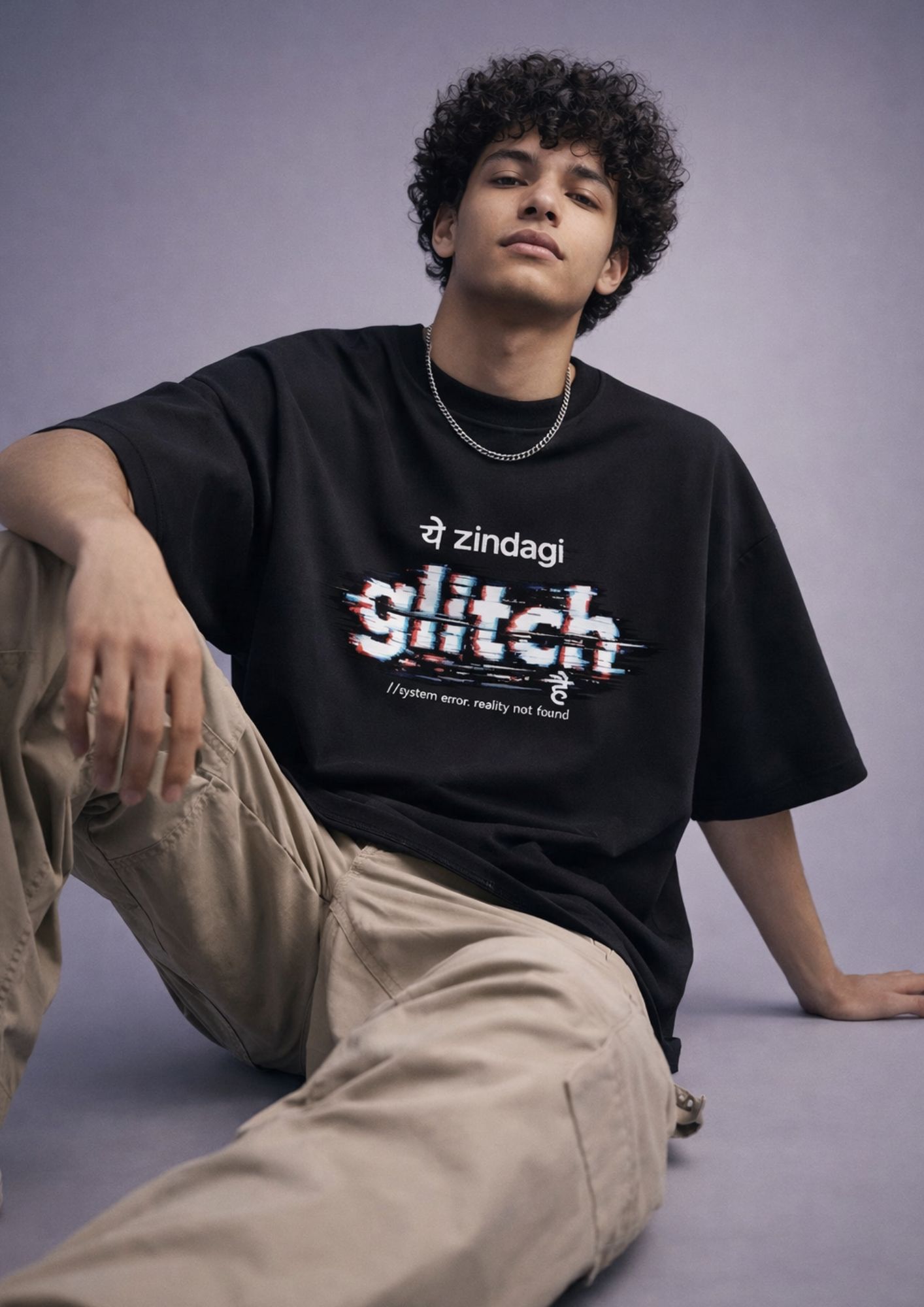 Male model wearing LUFIT oversized black t-shirt with graphic print, 240 GSM cotton fabric, styled with beige trousers in a minimal studio setting