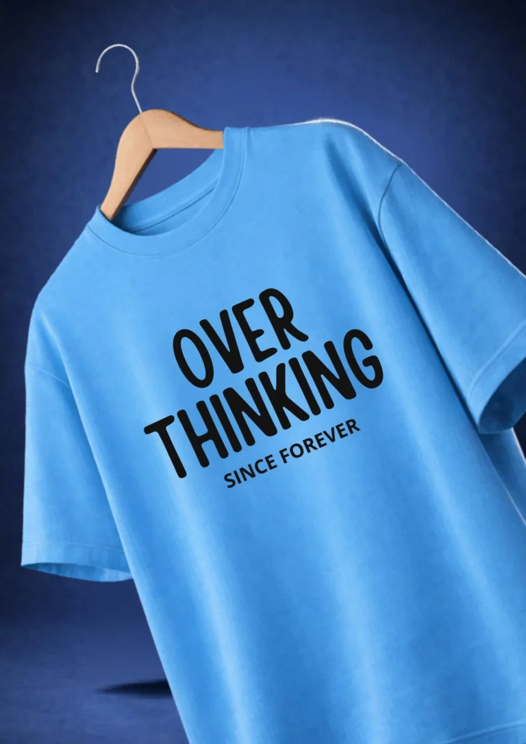 Sky blue oversized t-shirt with bold black typography print reading "Overthinking Since Forever" hanging on a wooden hanger against a dark blue background